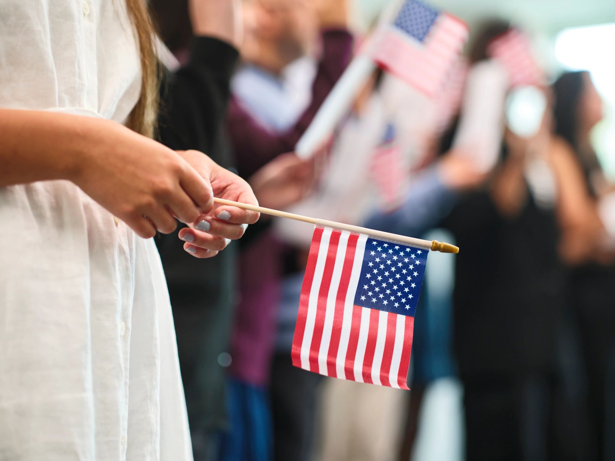 Diverse group of adults standing outdoors with an American flag, looking confident and united